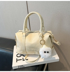 Detail of off-white faux leather handbag with fur ball charm and engraved logo