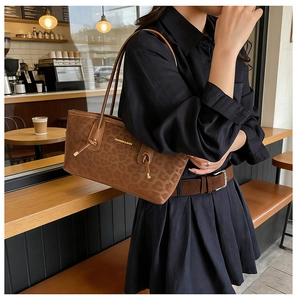 Détail du sac léopard avec bandoulière nouée et logo doré dans un café urbain chic