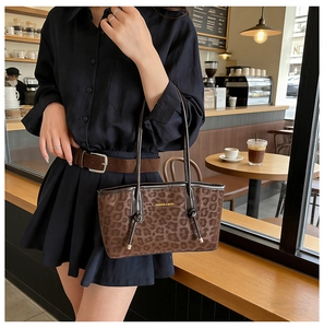 Détail d'un sac cabas imprimé léopard marron avec lettrage doré dans un décor de café