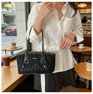 Détail d'un sac cabas léopard noir avec texte FASHION & BAGS dans un cadre de café