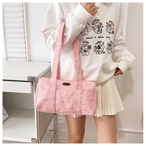 Lifestyle shot of pink canvas shoulder bag with star print and logo plaque for students
