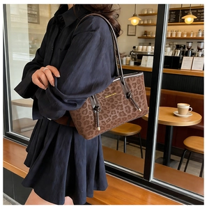 Gros plan d'un sac à bandoulière en daim léopard marron avec pompon dans un café vintage