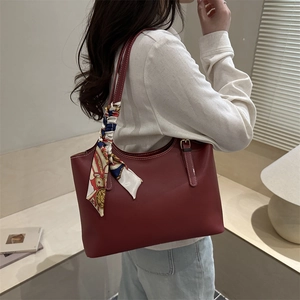 Vintage burgundy leather tote bag with decorative silk scarf on a female model