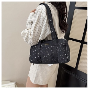 On-shoulder view of black Boston bag with white star pattern and wide straps