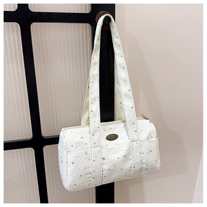 Detail of white cylinder shoulder bag featuring star prints and metallic handmade plaque