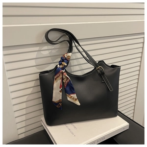 Detail of black matte tote bag featuring silver buckles and a colorful patterned silk scarf