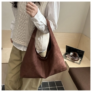 Detail of dark brown faux suede hobo bag with wide strap in a minimalist setting