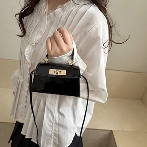 Fashionable black patent leather crossbody bag with top handle and gold clasp for women