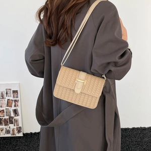 Sac bandoulière minimaliste en cuir tressé beige avec boucle dorée sur modèle