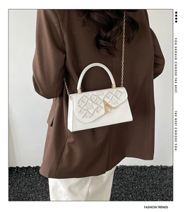 Détail du sac à main en cuir blanc avec boucle métallique en V dorée et bandoulière