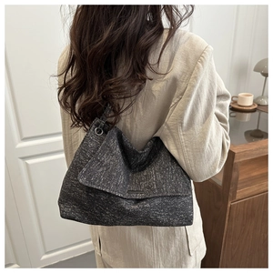 Close-up of a large dark grey tweed tote bag with metal bar detail and flap closure