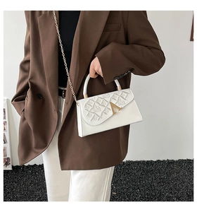 Sac bandoulière blanc à texture ondulée et chaîne dorée sur blazer marron élégant
