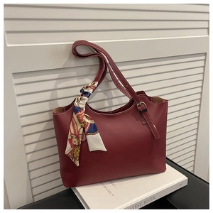 Close-up of burgundy leather tote with white contrast stitching and floral silk scarf detail