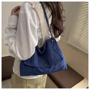 Detailansicht der großen blauen Denim-Tasche mit Metallkette getragen am Modell