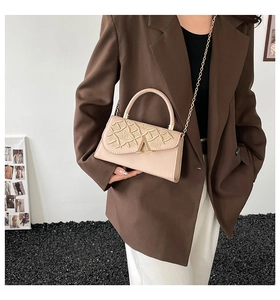 Détail du sac à main beige brodé avec fermoir en V doré et bandoulière en chaîne chic