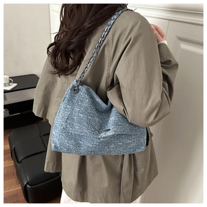 Detail of blue snowflake denim tote featuring a metallic chain strap and woven texture