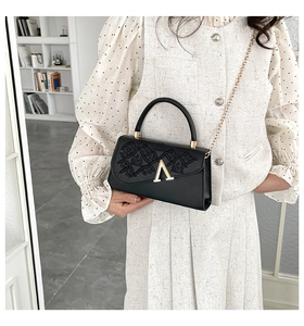Détail du sac bandoulière noir avec gaufrage géométrique et fermoir doré en V