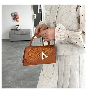 Détail d'un sac à main en similicuir marron avec broderie losange et fermoir doré