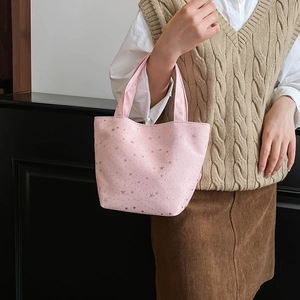 Close-up of pink canvas tote bag with silver sequin stars carried by a model