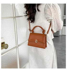 Rear view of model wearing a brown leather handbag with knotted handle and gold buckle