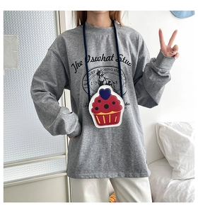 Red cupcake shaped crossbody bag with cream top and heart detail shown on model