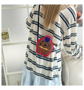 Detail of creative cupcake shaped crossbody bag with heart detail worn over stripes