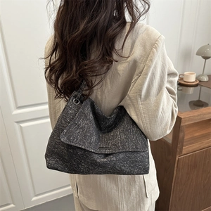 Grand sac cabas en denim gris avec chaîne porté par un mannequin dans un intérieur moderne