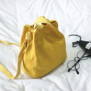 Minimalist yellow canvas bucket bag with adjustable shoulder strap and top handles
