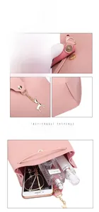 Detail of pink crossbody bag showing deer pendant, stitching, and interior capacity