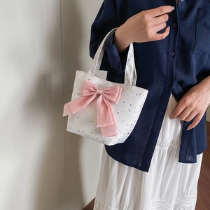 White canvas tote bag featuring a large pink bow and star pattern for a sweet fashion look