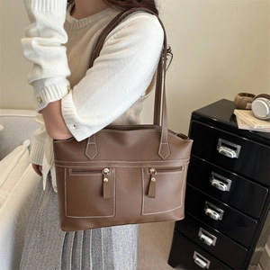 Sac cabas marron vintage avec coutures contrastées et poches zippées porté par mannequin