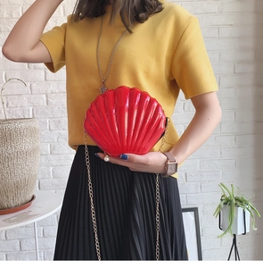 Detailed view of a red shell-shaped crossbody bag with a gold chain and pearl decoration