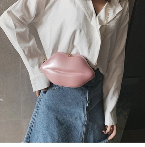 Close-up of a glossy pink lip-shaped crossbody bag with golden chain strap on a model