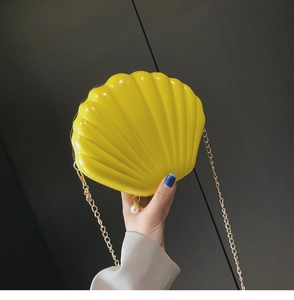 Detail of yellow shell-shaped acrylic crossbody bag with pearl accent and gold chain