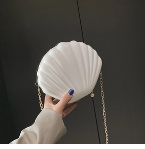 Macro shot of white shell acrylic bag with golden chain and pearl zipper detail