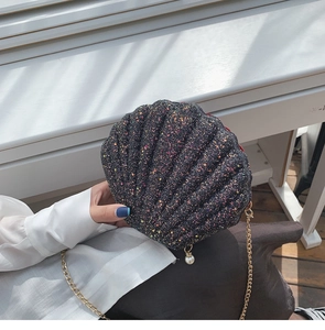 Close-up of black sequined seashell crossbody bag with pearl charm and gold chain strap