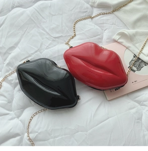 Detail of red and black lip-shaped patent leather crossbody bags with gold chain straps