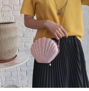 Detail of pink sequin shell-shaped crossbody bag with gold chain and pearl zipper