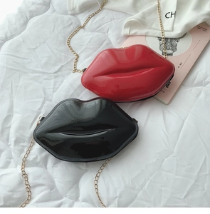 Detail of red and black lip-shaped crossbody bags with glossy finish and chain strap