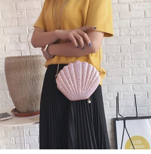 Detail of pink sequin shell-shaped bag with gold chain strap and pearl charm pendant