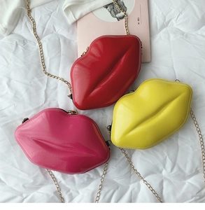 Detailed view of lip-shaped crossbody bags in glossy red, pink, and yellow with gold chains