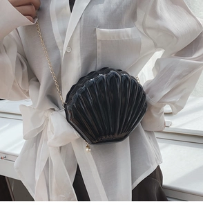 Detail of black shell-shaped crossbody bag with pearl zipper and gold chain strap