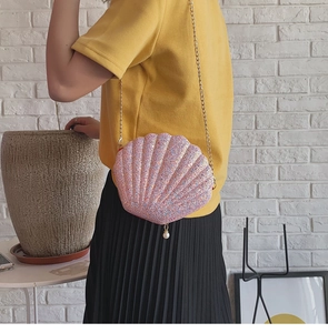 Detail of pink sequin shell crossbody bag with pearl pendant and gold chain strap