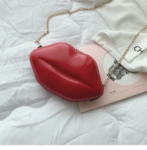 Detail of red lip-shaped clutch bag with glossy patent finish and gold chain strap