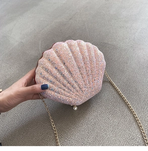 Detail of pink sequin shell-shaped bag with gold chain strap and pearl accent