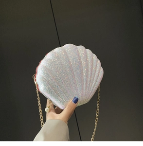 Close-up of shell-shaped iridescent glitter bag with gold chain and pearl charm detail