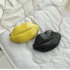 Detailed view of yellow and black lip-shaped mini chain bags in glossy patent leather