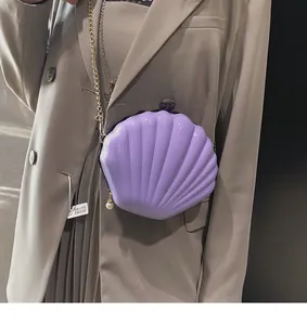 Detailed view of a purple shell-shaped acrylic bag with gold chain and pearl charm detail