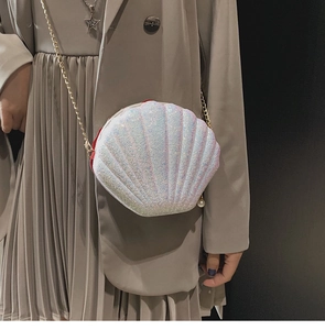 Detail of sequined shell crossbody bag with golden chain strap and pearl charm