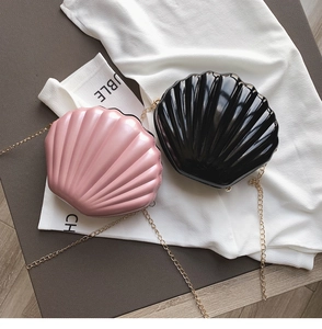 Detailed view of glossy shell-shaped handbags in pink and black with golden chains